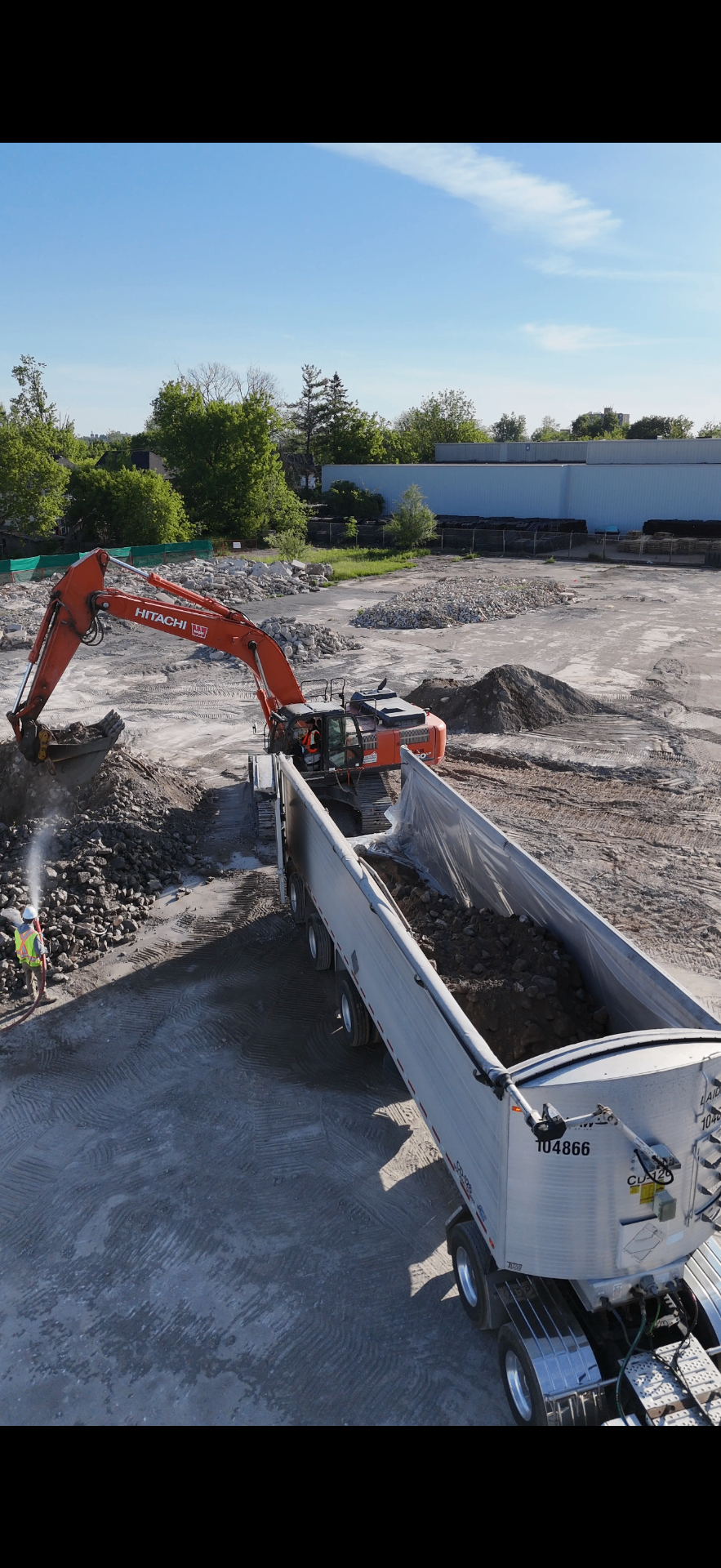 Aerial view of Hitachi excavator loading a dump trailer on an active remediation site