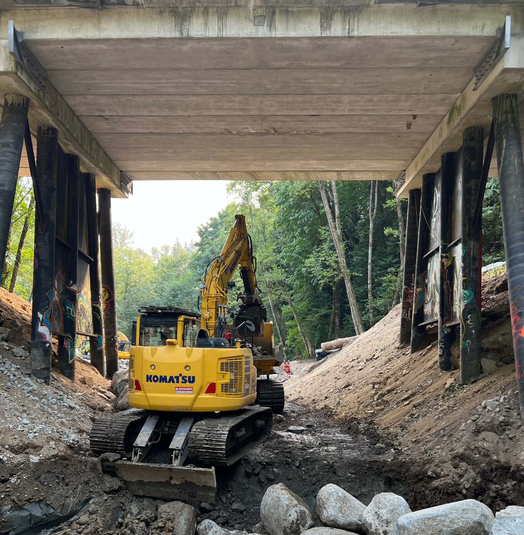 Komatsu excavator working under a bridge on channel and bank earthworks